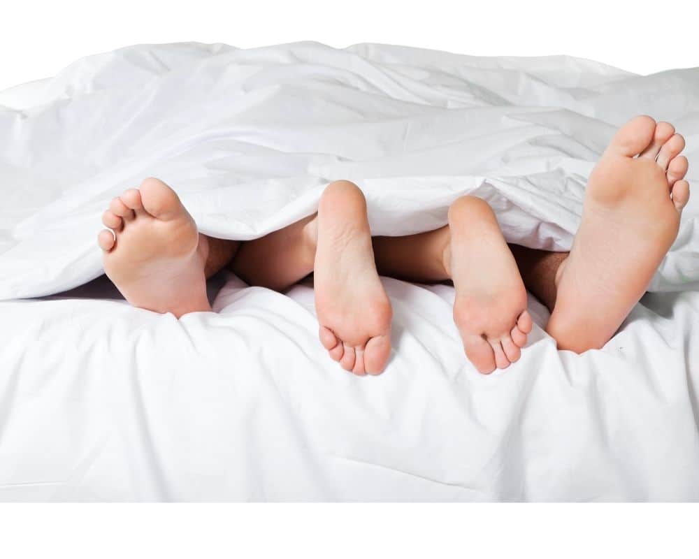 Kvinna och mans fötter i sängen 